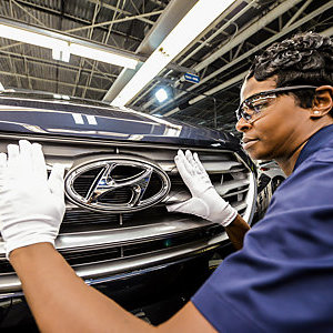 Hyundai worker woman polishing the front grille panel of a Hyundai car. 