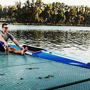 Smiling man who has a prosthetic leg, is sitting next to his kayak.