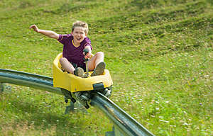 Boy going downhill at summer toboggan run - stock photo