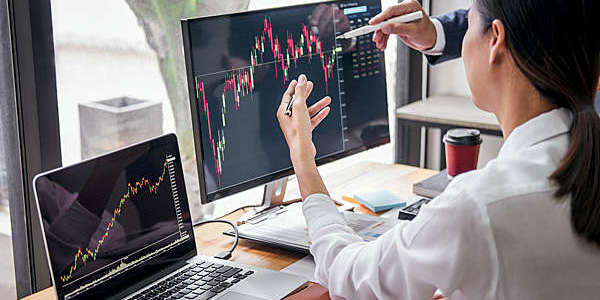 Side view of a young woman discussing a financial chart with a colleague (out of shot).