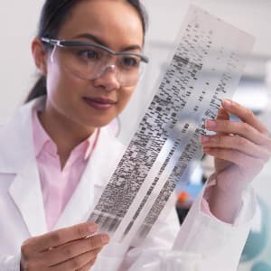 Female scientist examines a DNA profile in a laboratory.
