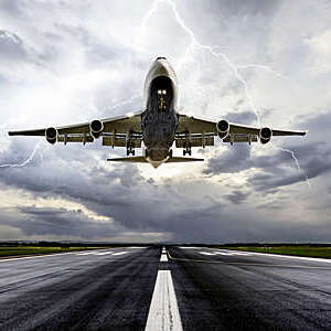 Low-angle shot of a passenger aircraft landing in extreme weather.